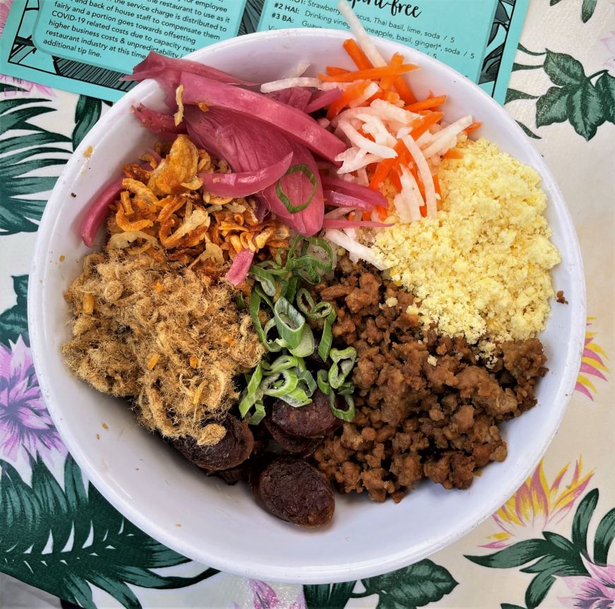 Bowl of sticky rice topped with colorful pickled vegetables, ground sausage, and pork floss
