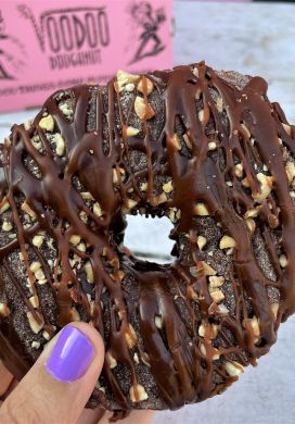 Raised doughnut topped with chocolate frosting and peanuts