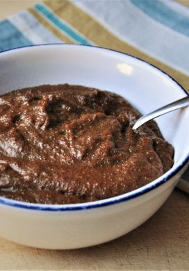 Cornmeal Molasses Pudding in bowl with spoon and napkin in background