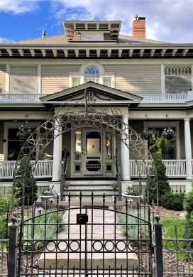 Exterior of two-story beige Victorian house with a porch