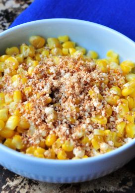 Bowl of corn topped with grated cheese and chipotle powder