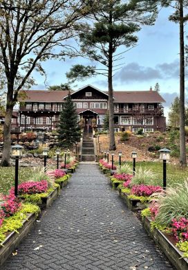 Flower lined path leading a large log-construction lodge building 