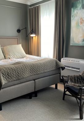 Bed and armchair in an upscale hotel room decorated in gray