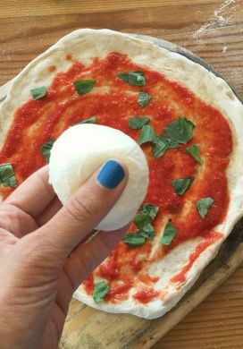 Hand holding mozzarella over uncooked pizza, 1889 Pizza Napoletana, Kansas City, Kansas