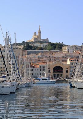 Marina filled with sailboats with a church on a hill in the background