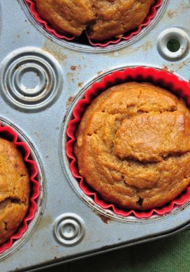 Pumpkin muffins in a tin with a green potholder