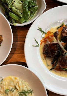 Top down view of dishes of prawns, snap peas, roasted duck, and orzo