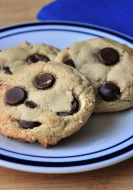 Three chocolate chip cookies on a small white plate with a blue edge