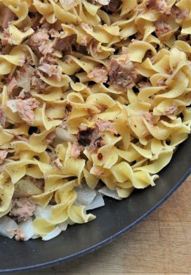Close up of egg noodles and canned tuna in a skillet
