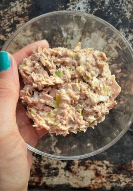 Hand holding glass bowl filled with tuna salad