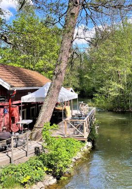 Red wooden cafe with a deck overlooking a river