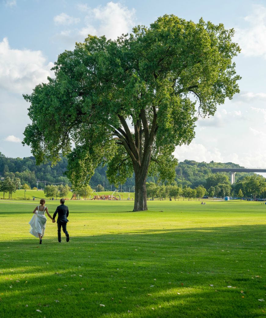 Stacy and Mike holding hands and running through a field