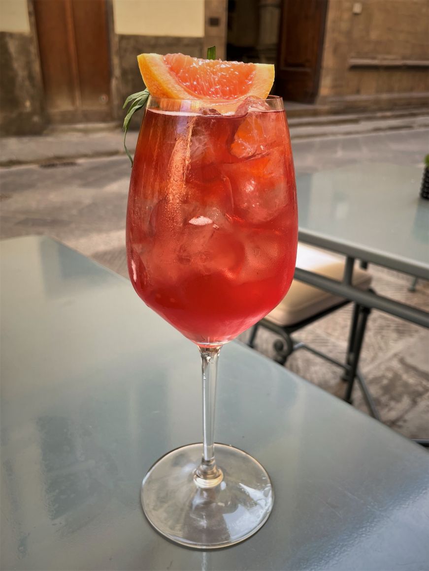 Pink cocktail garnished with a grapefruit slice and sprig of rosemary