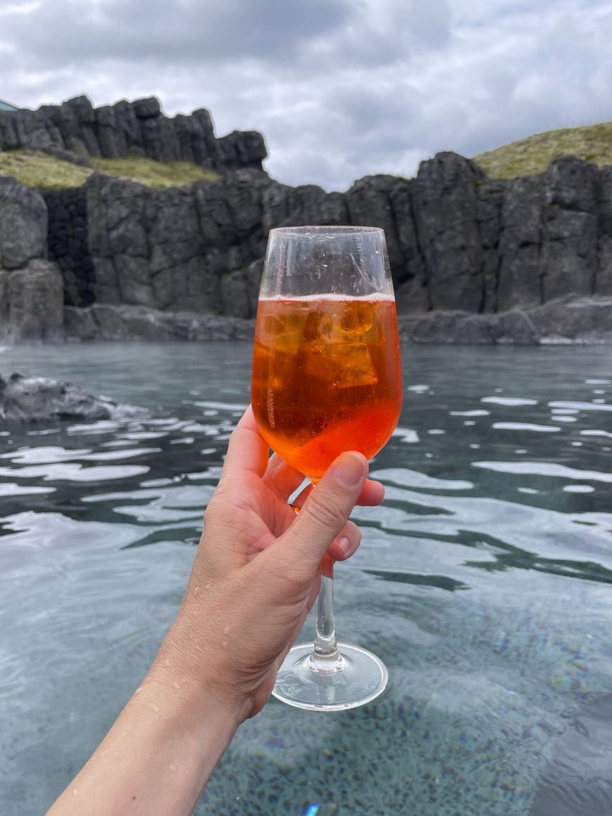 Stacy's hand holding an Aperol spritz at the Sky Lagoon