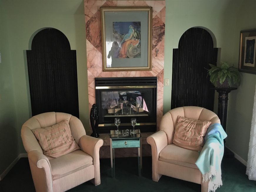 Two pink armchairs and a fireplace in an Art Deco-themed room