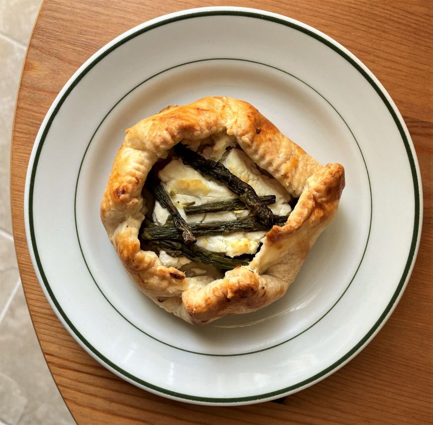 Personal-sized galette pastry filled with goat cheese and topped with small asparagus spears