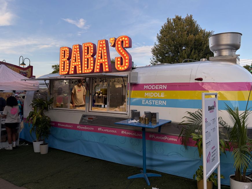 Baba's trailer, an Airstream with yellow, blue, and pink stripes and a retro sign with lights