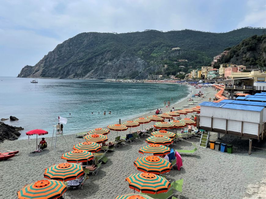 Sandy beach with green and orange striped umbrellas