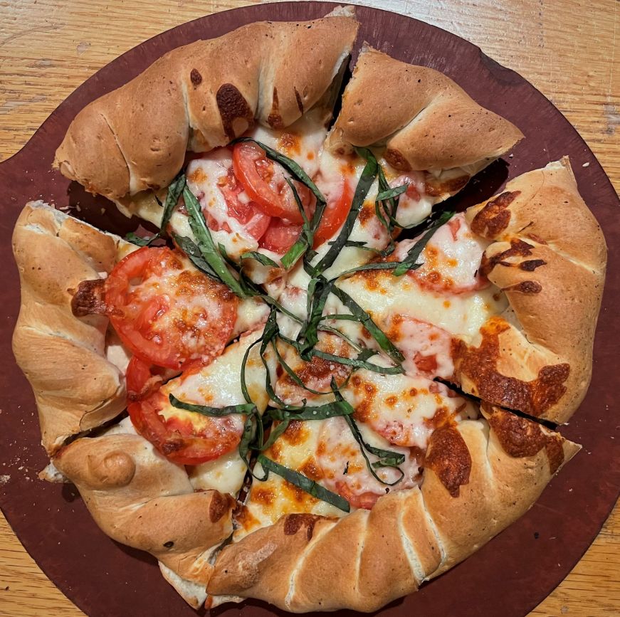 Top down view of an individually-sized margherita pizza with a thick rolled edge crust