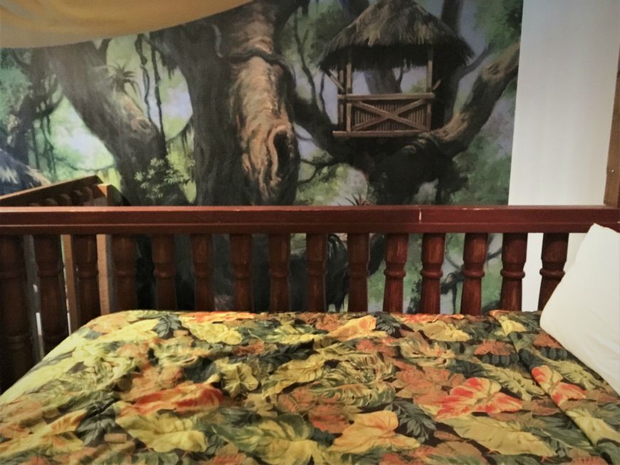 Bed with mural of treehouse in background in Castaway Isle Room, Chateau Avalon, Kansas City, Kansas