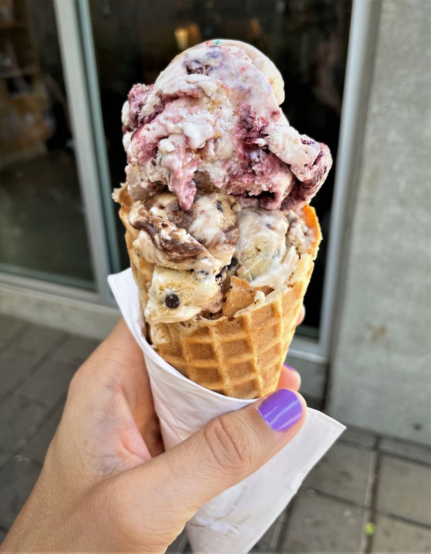 Stacy's hand holding a waffle cone with two scoops of ice cream