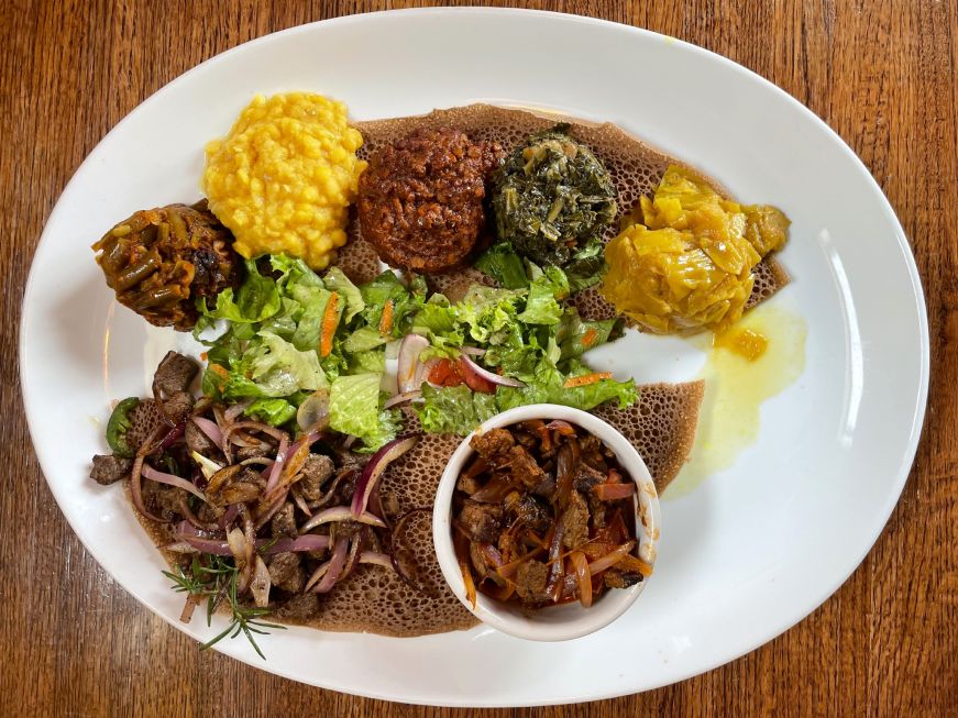 Meat and vegetarian stews arranged on a piece of injera