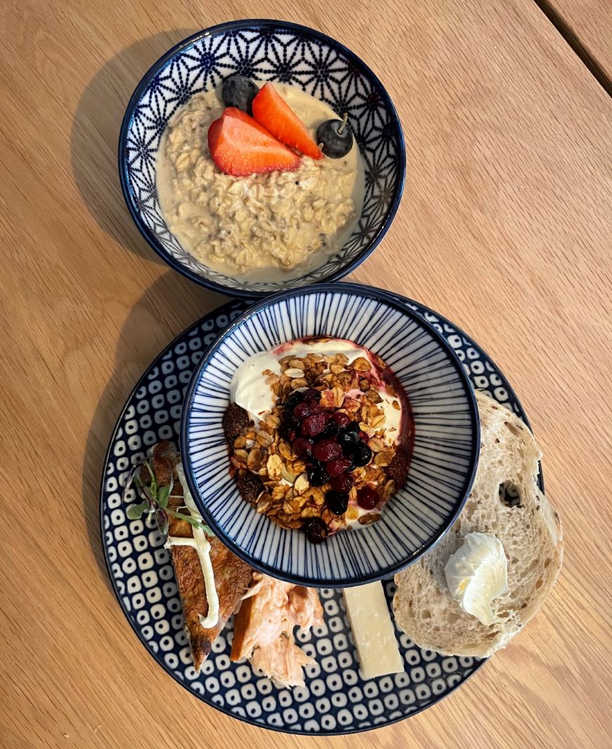 Breakfast at Lillan Hotel Bowl of muesli and plate with a yogurt parfait, smoked salmon, cheese, and bread