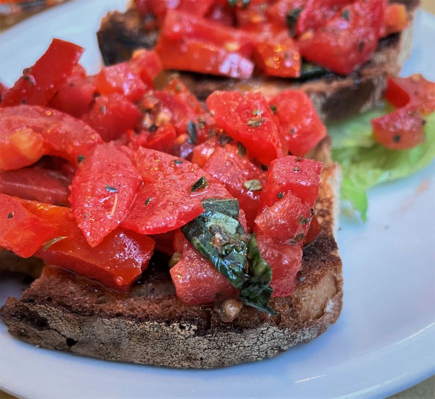 Pieces of bread topped with chopped tomatoes and basil