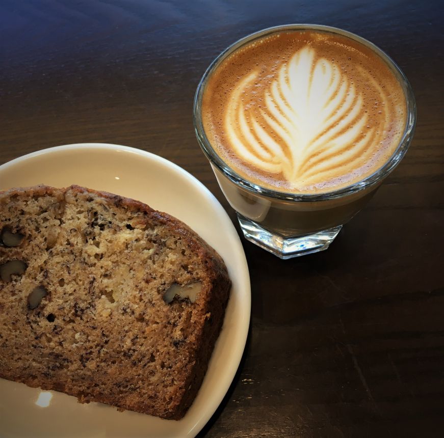 Slice of banana bread on plate and cortado with latte art, Buddy Brew Coffee, Tampa