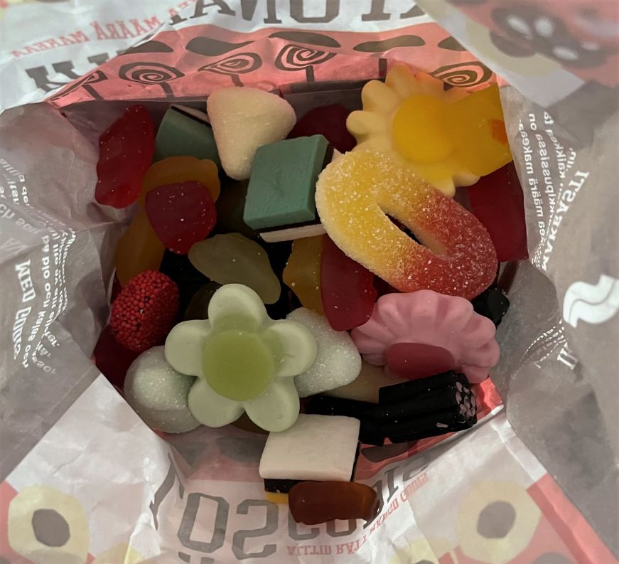 Paper bag filled with colorful gummies and black licorice