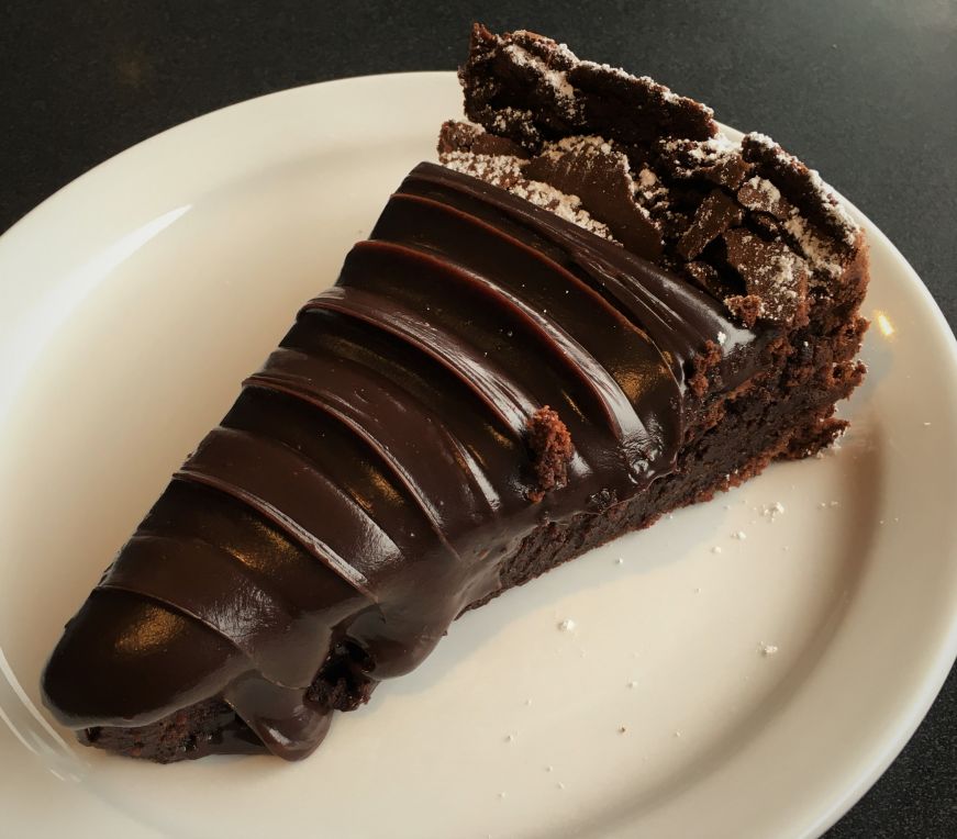 Plate with a slice of dense chocolate cake with a thick layer of frosting