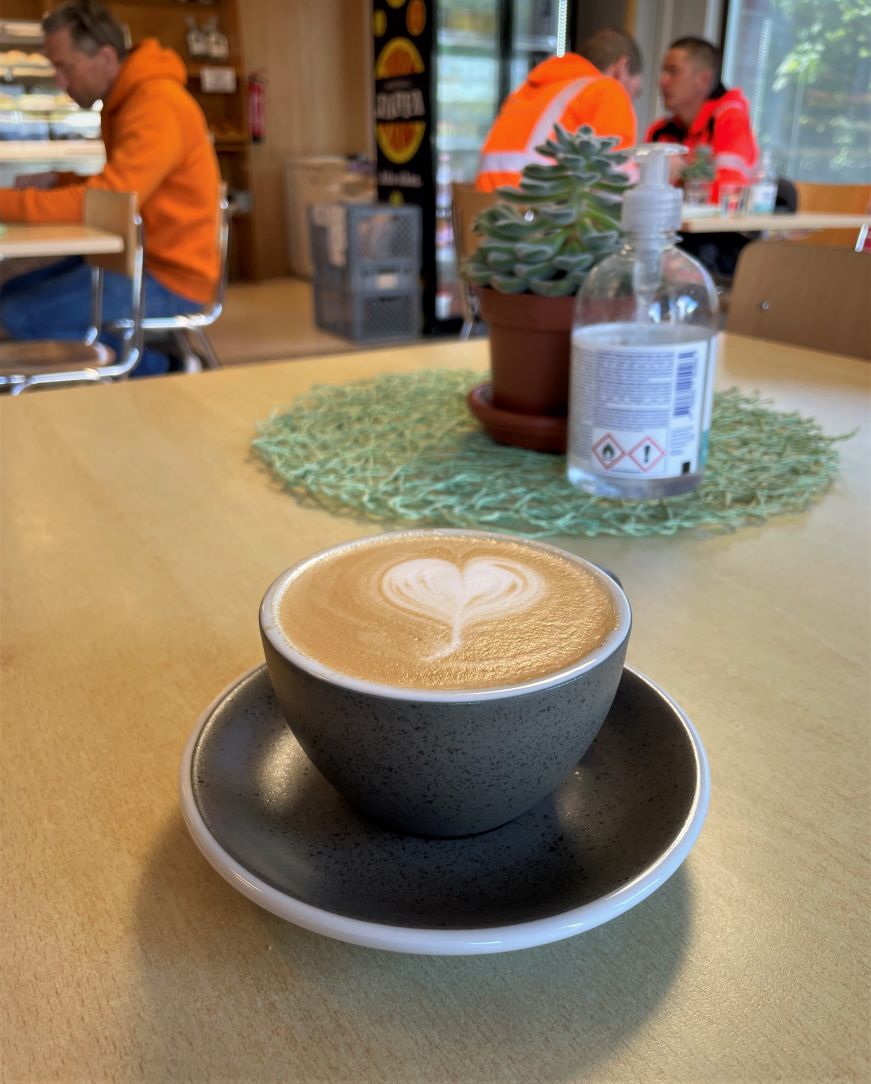 Cappuccino on a diner table with construction workers sitting at tables in the background