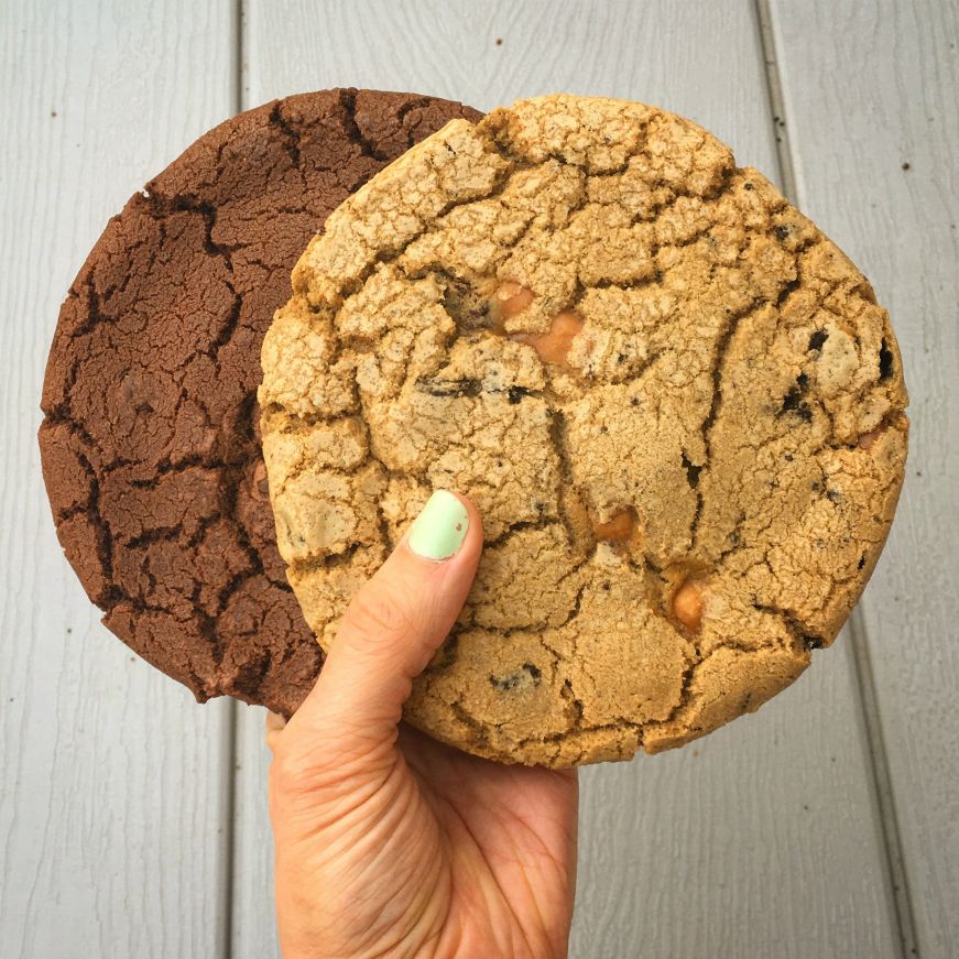 Chocolate chocolate chip and caramel Oreo cookies, T-Rex Cookie Kitchen Hand holding two huge cookies