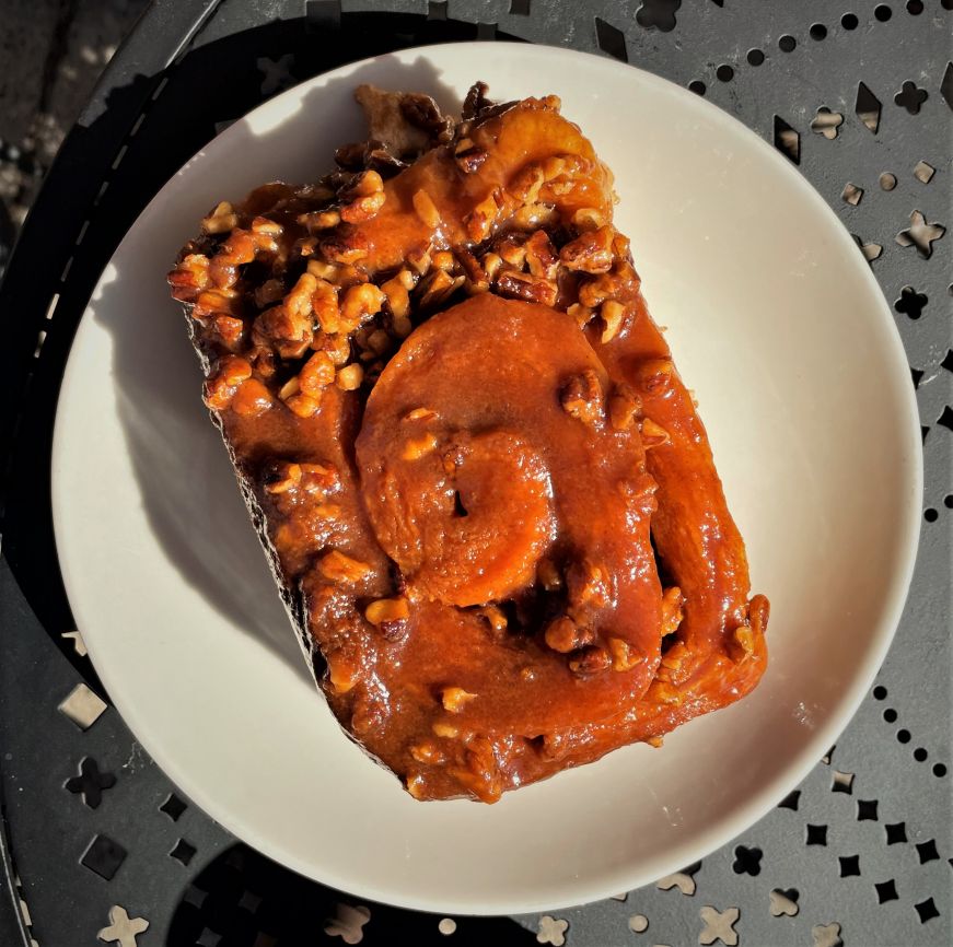 Caramel roll, Coffee Paw Cafe Large caramel roll with pecans on a white plate