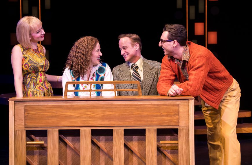 Four people sitting on a piano bench