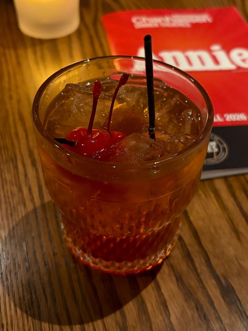 Manhattan in a rocks glass with ice cubes and cherry garnish