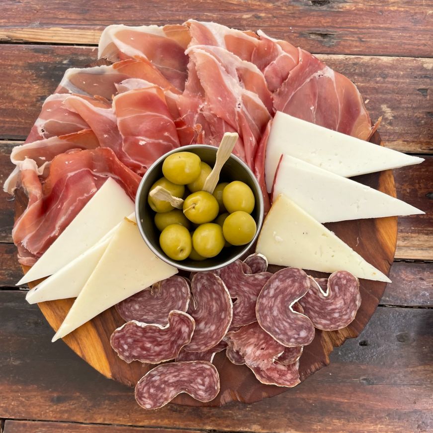 Top down view of a round plate filled with slices of cheese and charcuterie