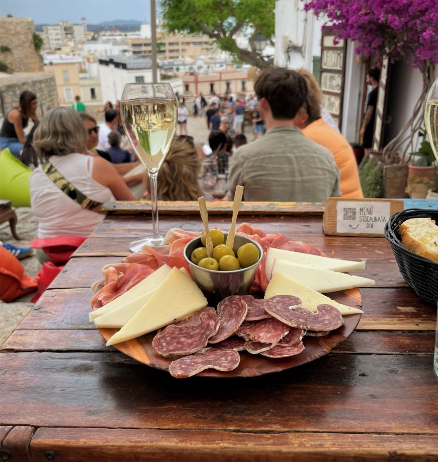 Plate of cured meats, cheese, and olives and a glass of wine