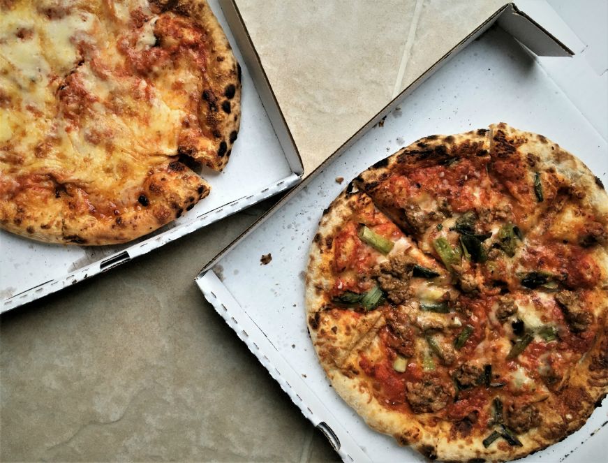 Individually-sized cheese and sausage pizzas in boxes