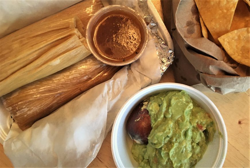 Three cheese and jalapeno tamales, bowl of guacamole, and paper bag of tortilla chips