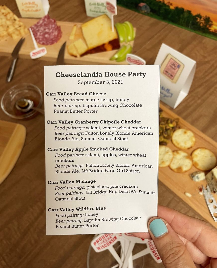 Hand holding a small piece of paper listing cheeses and their food and beverage pairings