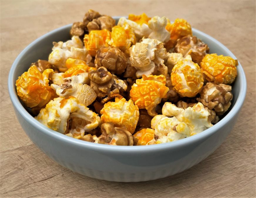 Blue ceramic bowl filled a mixture of cheese, seasoned, and caramel popcorn