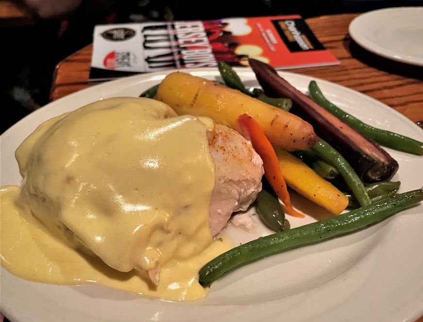 Chicken breast covered with hollandaise sauce with roasted carrots and green beans on the side