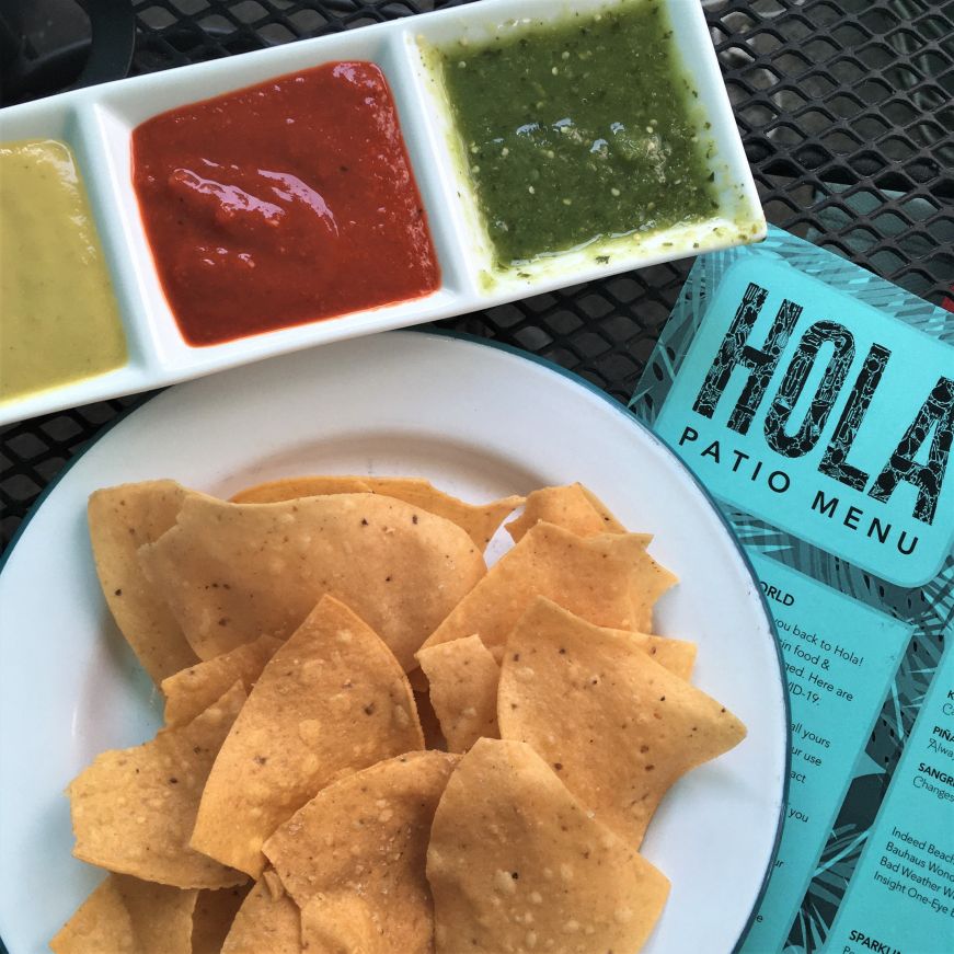 Serving dish with three types of salsa, chips, and menu