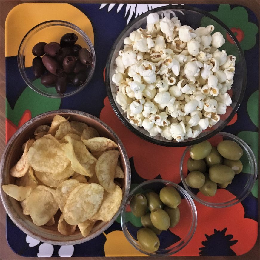 Tray with bowls of popcorn, chips, and olives