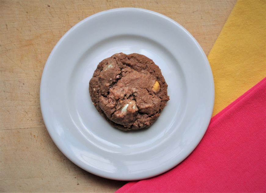 Chocolate Cadbry Mini Egg cookie on plate with yellow and pink napkins in the backgroun