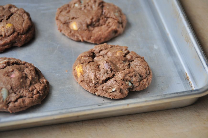 Chocolate cookies with multi-colored candies on a baking sheet