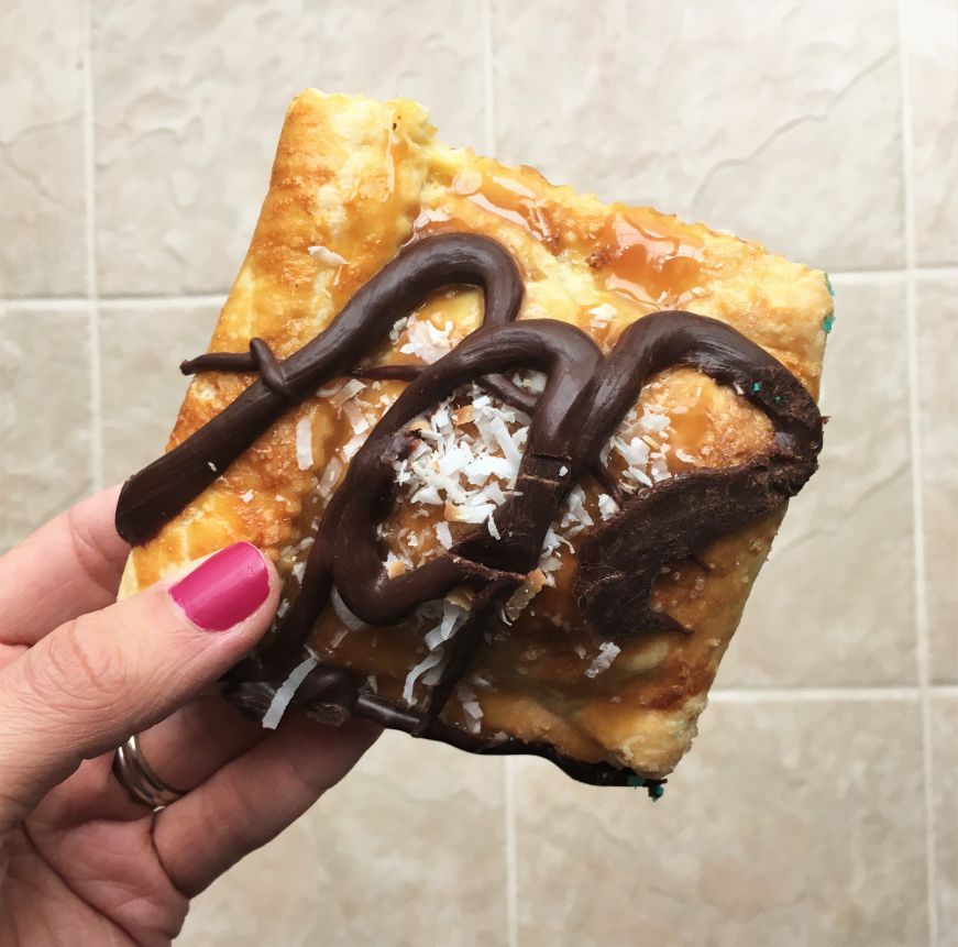 Hand holding gourmet pop tart drizzled with chocolate 