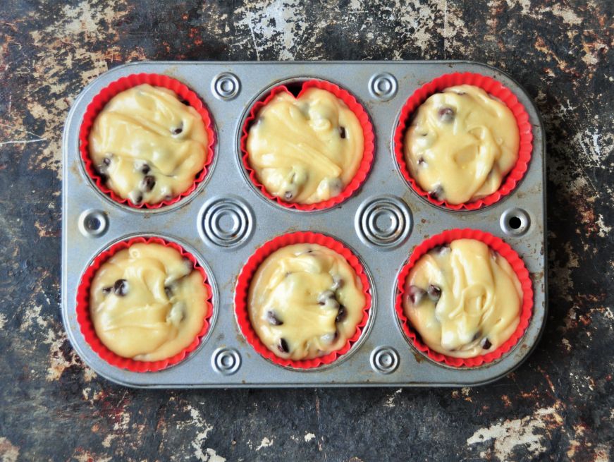 Muffin tin filled with chocolate chip muffin batter