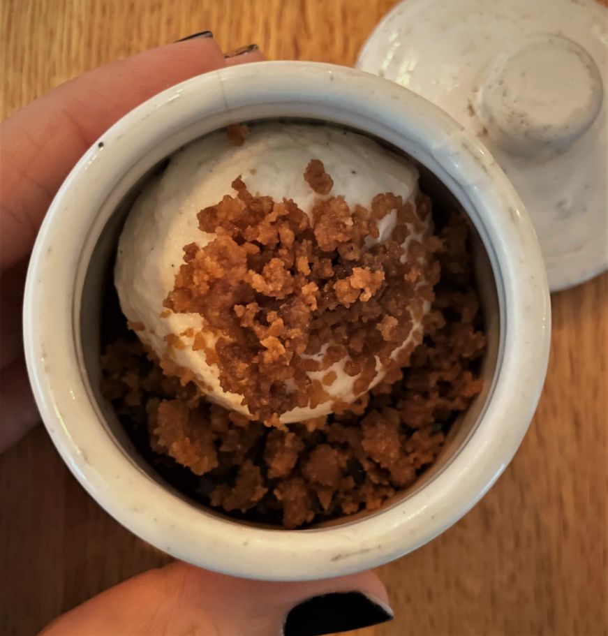 Small cup filled with custard and topped with whipped cream and streusel